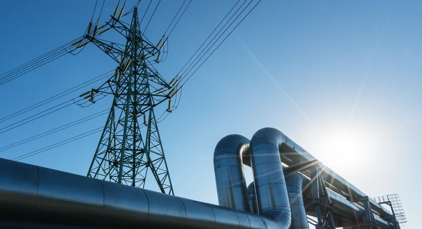 Hochspannungsmast und Rohrleitungen als Symbol für Strom- und Gasnetze